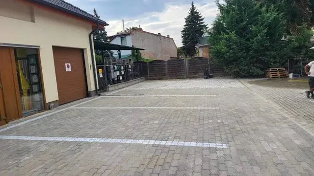 Térkövezett parkoló fehér térkősorral jelölt parkolóhelyekkel üzlethelyiség előtt