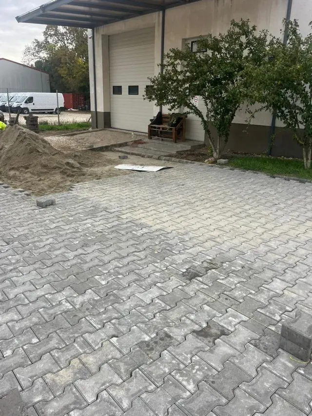 Behaton térkő burkolat raktár szekcionált kapuja előtt, ágyazóhomok-depóval